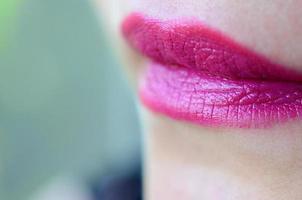 Close up shot of woman lips with glossy fuchsia lipstick photo