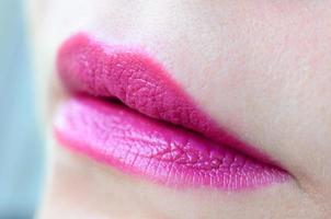 Close up shot of woman lips with glossy fuchsia lipstick photo