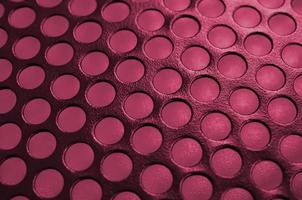 Black metal computer case panel mesh with holes on background. Abstract close up image Image toned in Viva Magenta, color of the 2023 year photo