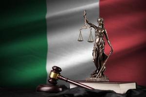 Italy flag with statue of lady justice, constitution and judge hammer on black drapery. Concept of judgement and guilt photo