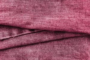Detailed abstract texture of dark blue denim cloth. Background image of old used denim trousers fabric Image toned in Viva Magenta, color of the 2023 year photo
