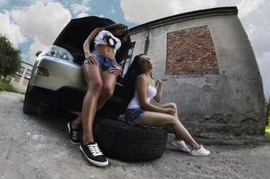 dos chicas jóvenes y sexys con llaves de rueda alrededor de una ca plateada foto