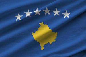 bandera de kosovo con grandes pliegues ondeando de cerca bajo la luz del estudio en el interior. los símbolos y colores oficiales en banner foto