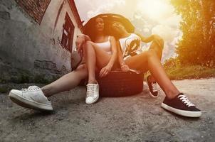 Two young and sexy girls with wheel wrenches around a silvery ca photo