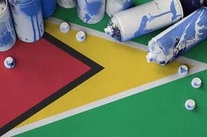 bandera de guyana y pocas latas de aerosol usadas para pintar graffiti. concepto de cultura de arte callejero foto