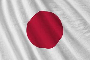 Japan flag with big folds waving close up under the studio light indoors. The official symbols and colors in banner photo