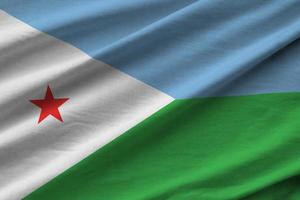 Djibouti flag with big folds waving close up under the studio light indoors. The official symbols and colors in banner photo