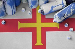 Guernsey flag and few used aerosol spray cans for graffiti painting. Street art culture concept photo