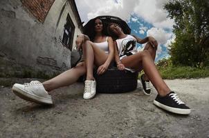 Two young and sexy girls with wheel wrenches around a silvery ca photo