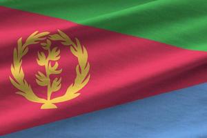 Eritrea flag with big folds waving close up under the studio light indoors. The official symbols and colors in banner photo