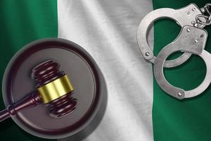 Nigeria flag with judge mallet and handcuffs in dark room. Concept of criminal and punishment, background for judgement topics photo