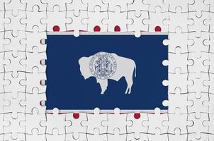 Wyoming US state flag in frame of white puzzle pieces with missing central part photo