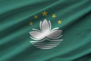 Macau flag with big folds waving close up under the studio light indoors. The official symbols and colors in banner photo