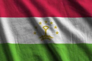 Tajikistan flag with big folds waving close up under the studio light indoors. The official symbols and colors in banner photo
