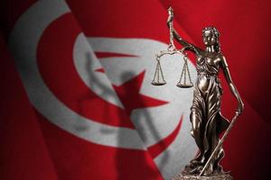 Tunisia flag with statue of lady justice and judicial scales in dark room. Concept of judgement and punishment photo