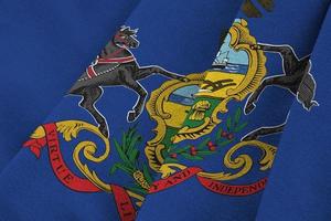 pennsylvania bandera del estado de estados unidos con grandes pliegues ondeando de cerca bajo la luz del estudio en el interior. los símbolos y colores oficiales en banner foto