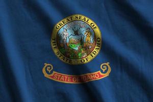 Idaho US state flag with big folds waving close up under the studio light indoors. The official symbols and colors in banner photo