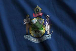 Maine US state flag with big folds waving close up under the studio light indoors. The official symbols and colors in banner photo