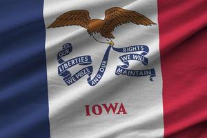 Iowa US state flag with big folds waving close up under the studio light indoors. The official symbols and colors in banner photo