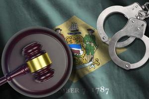 Delaware US state flag with judge mallet and handcuffs in dark room. Concept of criminal and punishment photo