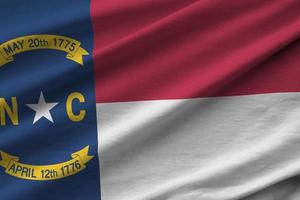 North Carolina US state flag with big folds waving close up under the studio light indoors. The official symbols and colors in banner photo