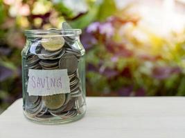 Coins in glass bottles on nature background. The concept of savings and investment. photo