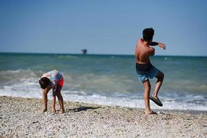 Two brothers throw pebbles into the sea in beach Porto Sant Elpidio, Italy. photo