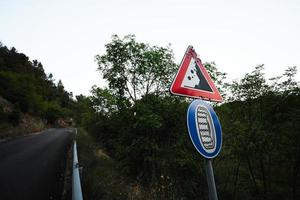 señales de tráfico que caen piedras, señales de tráfico precaución posible caída de rocas con cadenas de nieve obligatorias a bordo del coche en invierno. foto