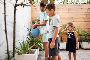 Children with can watering the flowers on the terrace of the house. photo