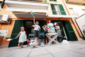 felices cuatro niños con banderas italianas celebrando el día de la república de italia. foto