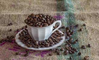 A cup of coffee full of coffee beans on a tat photo