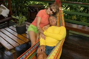 hombre maduro con una camisa amarilla brillante relajándose en una hamaca colorida con su esposa foto