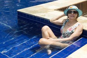 mujer relajándose en la piscina con un sombrero azul y sombras foto