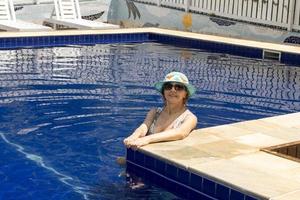mujer relajándose en la piscina con un sombrero azul y sombras foto