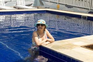 mujer relajándose en la piscina con un sombrero azul y sombras foto