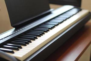 Black piano keyboard with white keys against window interior background photo