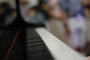 Black piano keyboard with white keys against window interior background photo