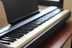 Black piano keyboard with white keys against window interior background photo