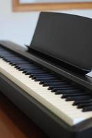 Black piano keyboard with white keys against window interior background photo