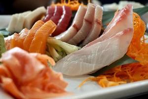 Various menus, sushi, sashimi, nigiri, pan fried pork and miso soup. Sashimi, chutoro sashimi, Japanese food chopsticks and wasabi on the black table, Japanese food style. blurs focus. photo