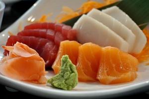 Various menus, sushi, sashimi, nigiri, pan fried pork and miso soup. Sashimi, chutoro sashimi, Japanese food chopsticks and wasabi on the black table, Japanese food style. blurs focus. photo