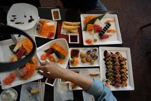 varios menús, sushi, sashimi, nigiri, cerdo frito y sopa de miso. sashimi, chutoro sashimi, palillos de comida japonesa y wasabi en la mesa negra, estilo de comida japonesa. desdibuja el foco. foto