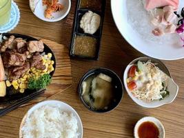 Various menus, sushi, sashimi, nigiri, pan fried pork and miso soup. Sashimi, chutoro sashimi, Japanese food chopsticks and wasabi on the black table, Japanese food style. blurs focus. photo