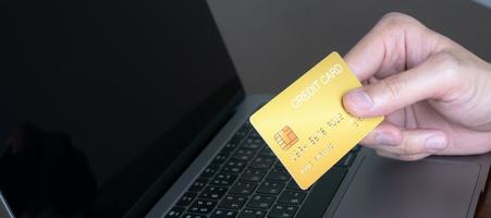 manos con tarjeta de crédito y usando una computadora portátil o móvil, compras en línea, comercio electrónico, banca por Internet, gastar dinero, trabajar desde el concepto de hogar foto