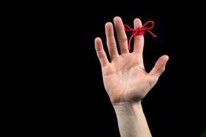 The open right hand with the reminder string tied to index finger isolated on black photo