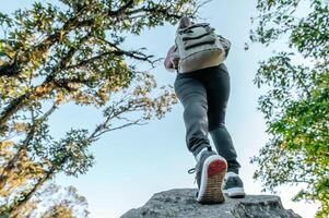 mujer joven excursionista caminando sobre la pendiente de las rocas foto