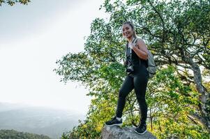 mujer joven excursionista de pie en la vista rocosa y mirando foto