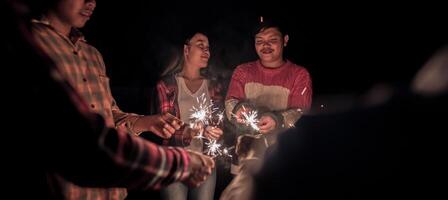 mujer joven jugando fuegos artificiales quemando bengalas con amigos foto