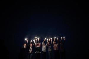Group of young friends holding and play with fire burning sparklers photo