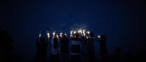 Group of young friends holding and play with fire burning sparklers photo